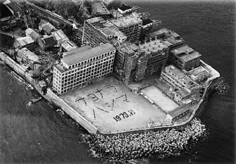 Black-and-white aerial view of fortified man-made island with buildings and Hebrew 1973 marking.