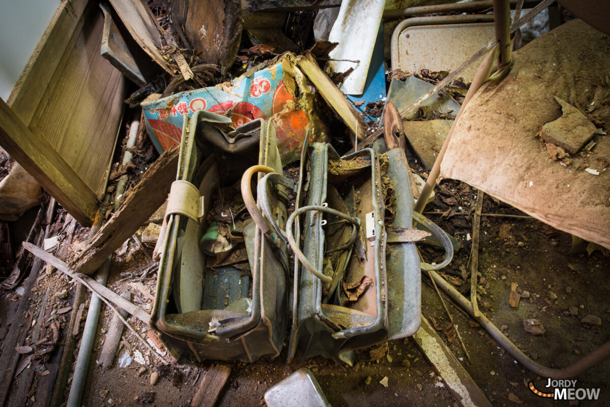 Dusty medical bags and tubes amid debris in abandoned clinic, rust-stained and decaying.