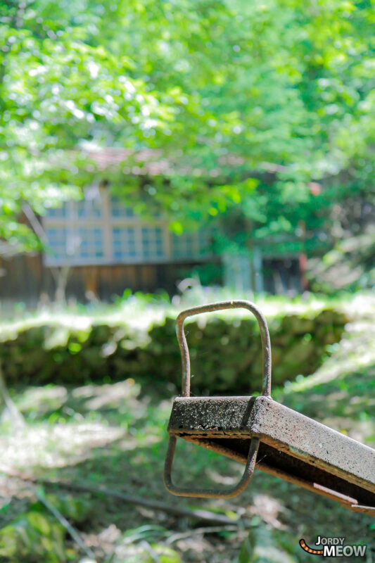 Rusty desk handle foreground with abandoned Namezawa School in rural Yamanashi near Mount Fuji.