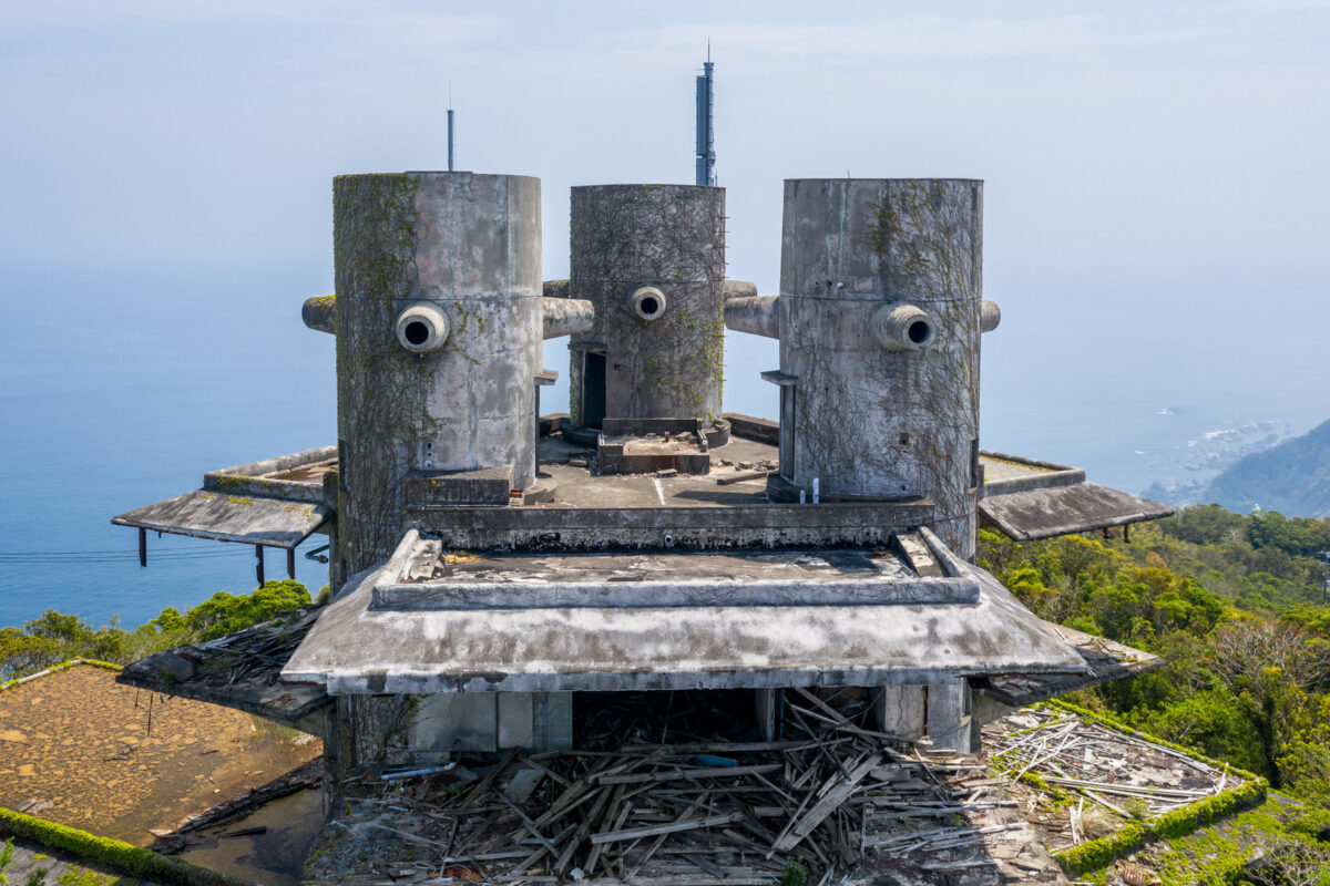 Abandoned New Muroto Sky Resort towers overlooking Japan’s Pacific coast and green hills.