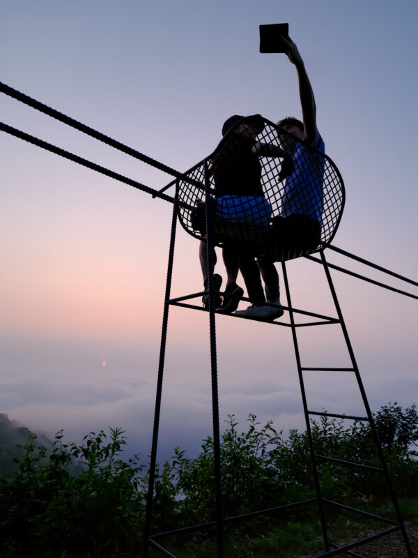 Two silhouettes on Unkai Terrace tower above a twilight sea of clouds.