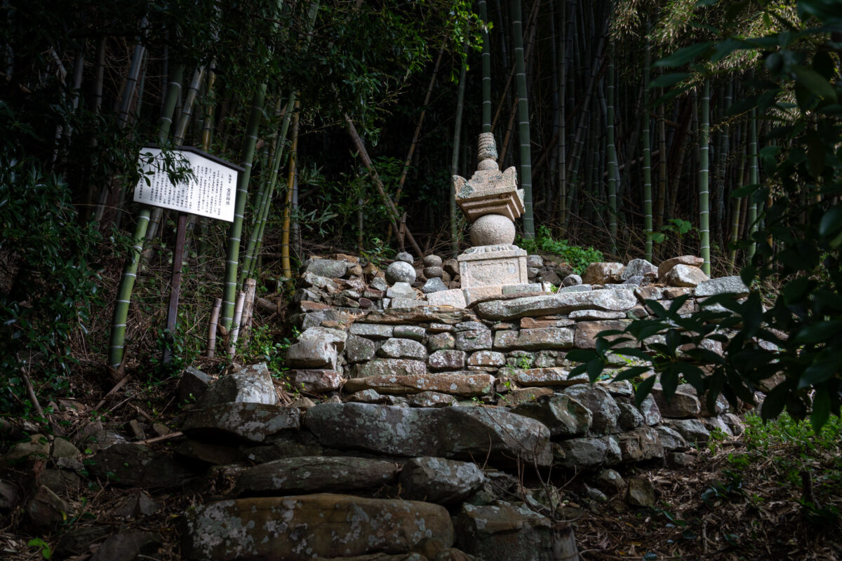 Stone shrine and rock altar in dense bamboo forest with nearby information sign
