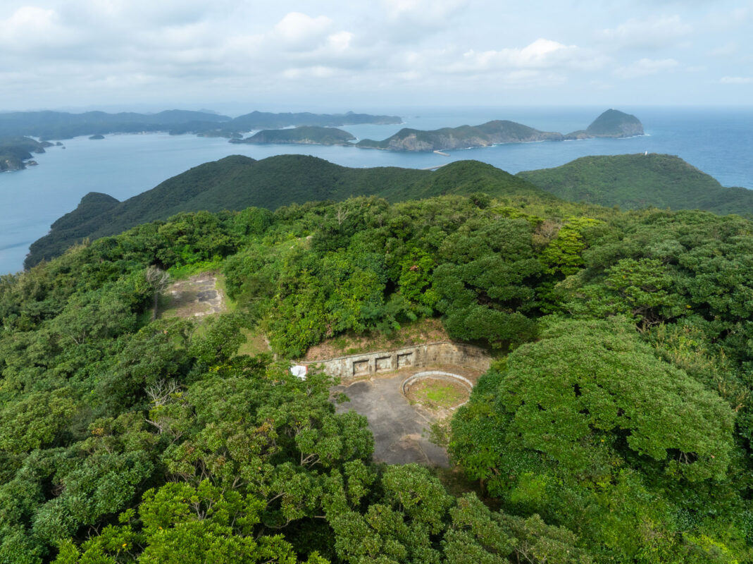 Aerial view of Himegamiyama forest and coastal islands, with stone ruins overlooking calm water.