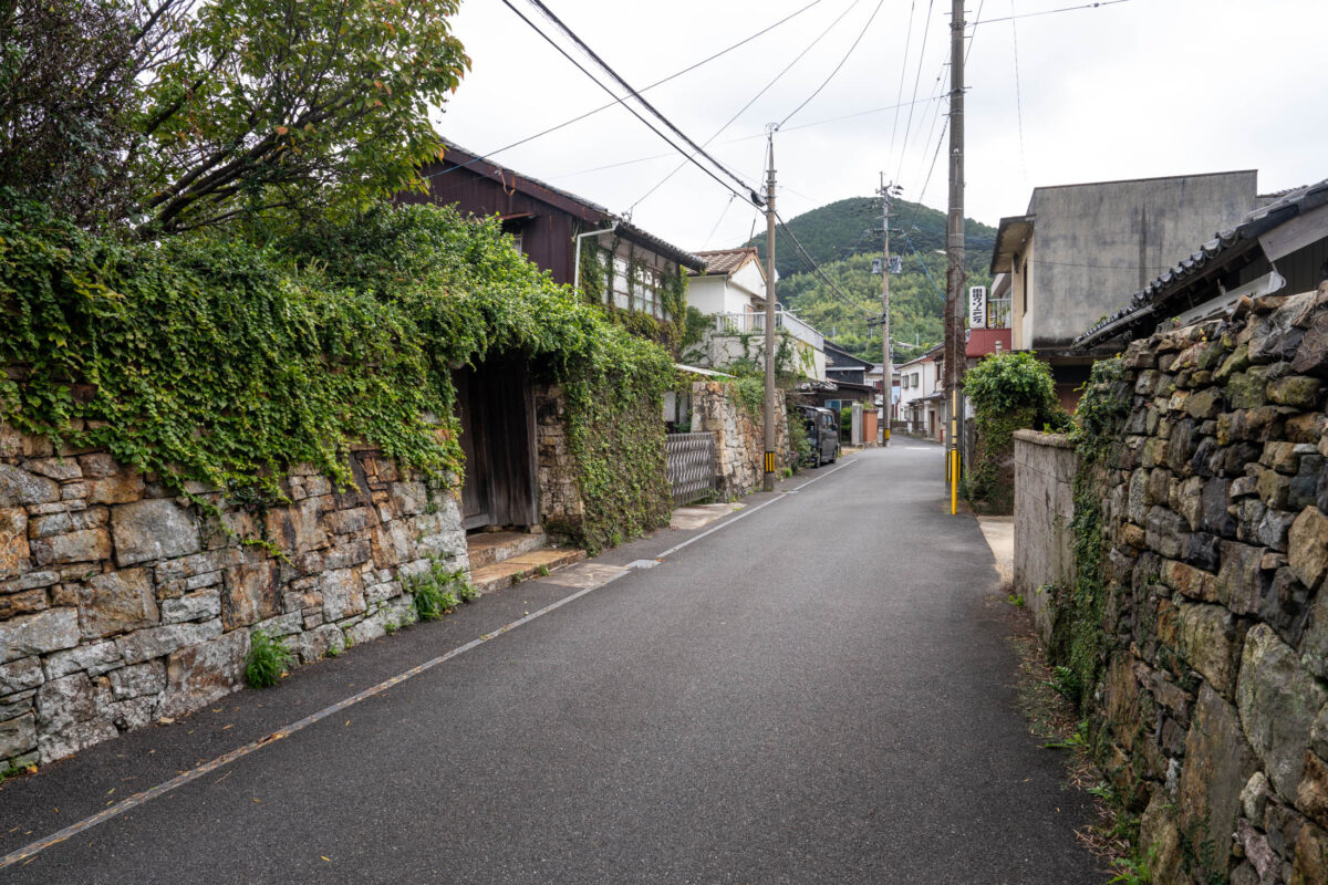 Quiet street in Izuhara, Japan with stone walls, ivy, and hillside view