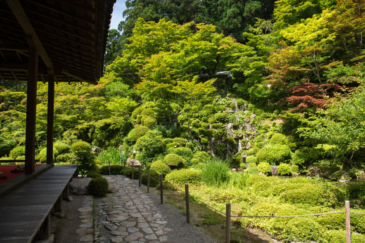 Stone path and lush garden at Kongōrin-ji Temple, Japan, beside wooden veranda.
