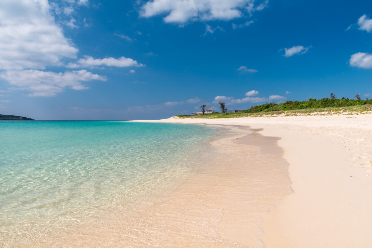 Pristine Miyako Island beach with powdery sand and crystal-clear turquoise water under blue sky.