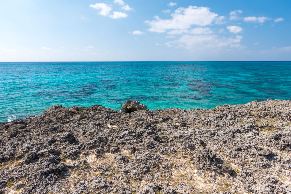 Rocky shore on Miyako Island with crystal-clear turquoise water and blue sky.