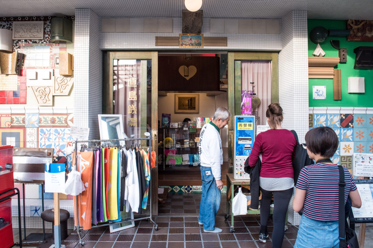 Visitors queue outside Naoshima art shop with colorful tiled facade and open entrance.