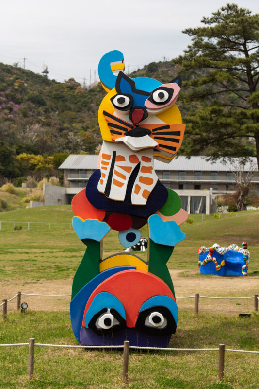 Colorful totem sculpture with cat figure in grassy field, Naoshima Island Japan