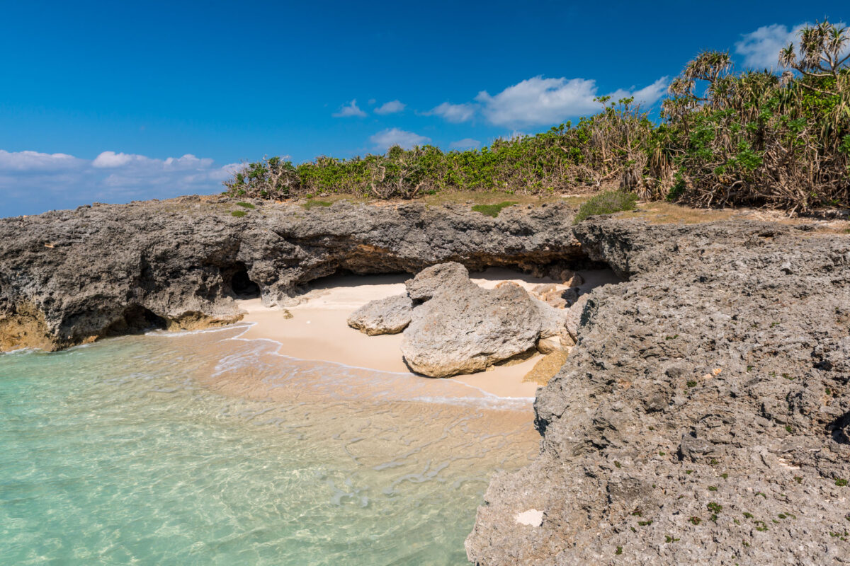Turquoise rocky cove with clear water and coastal shrubs on Miyako Island, Japan.