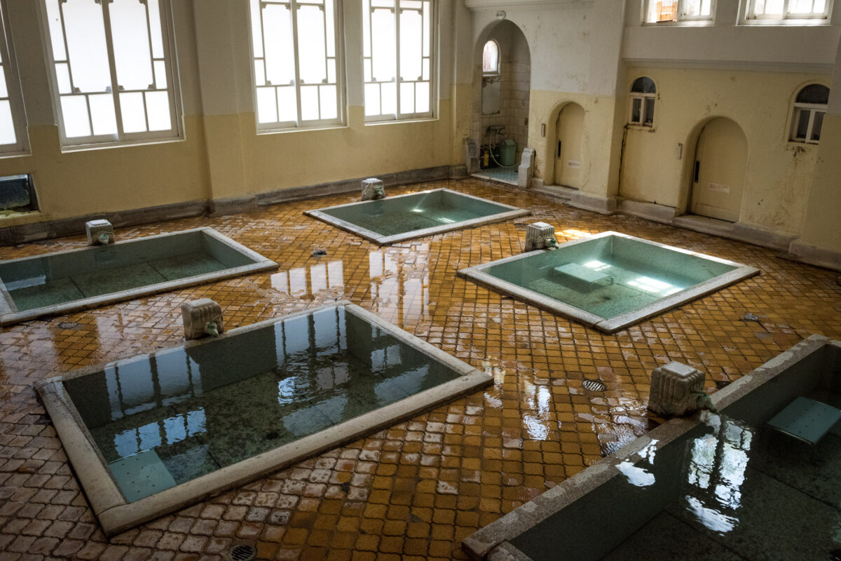 Traditional onsen bath hall at Sekizenkan Ryokan with square soaking pools and tall windows.