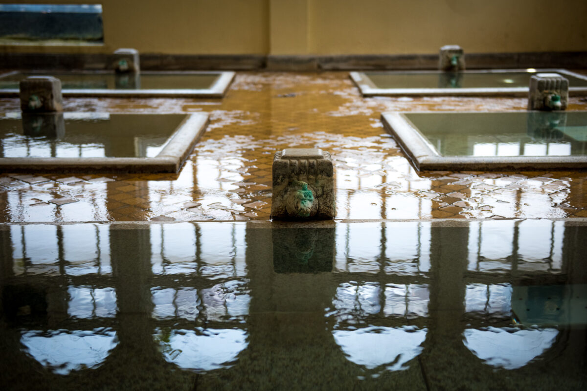 Indoor onsen pool at Sekizenkan Ryokan with clear water, stone baths, and window reflections.