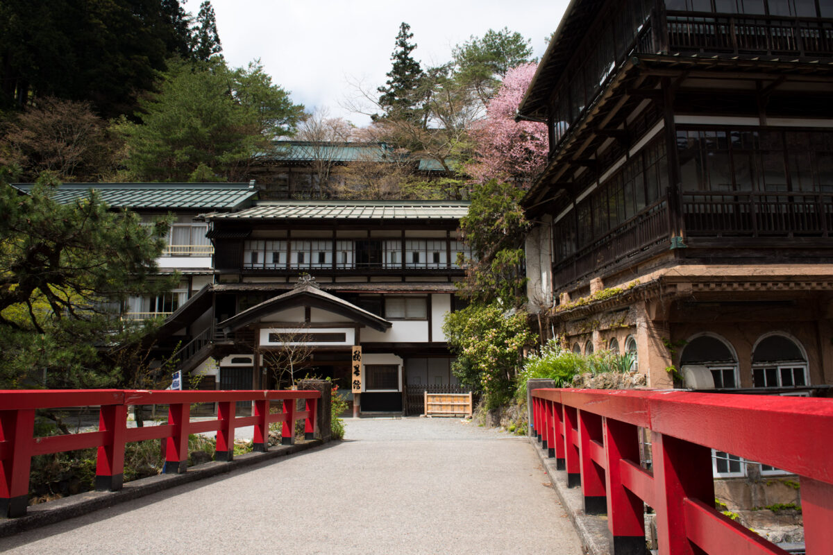 Red bridge entrance to Sekizenkan Ryokan traditional Japanese mountain inn surrounded by forest