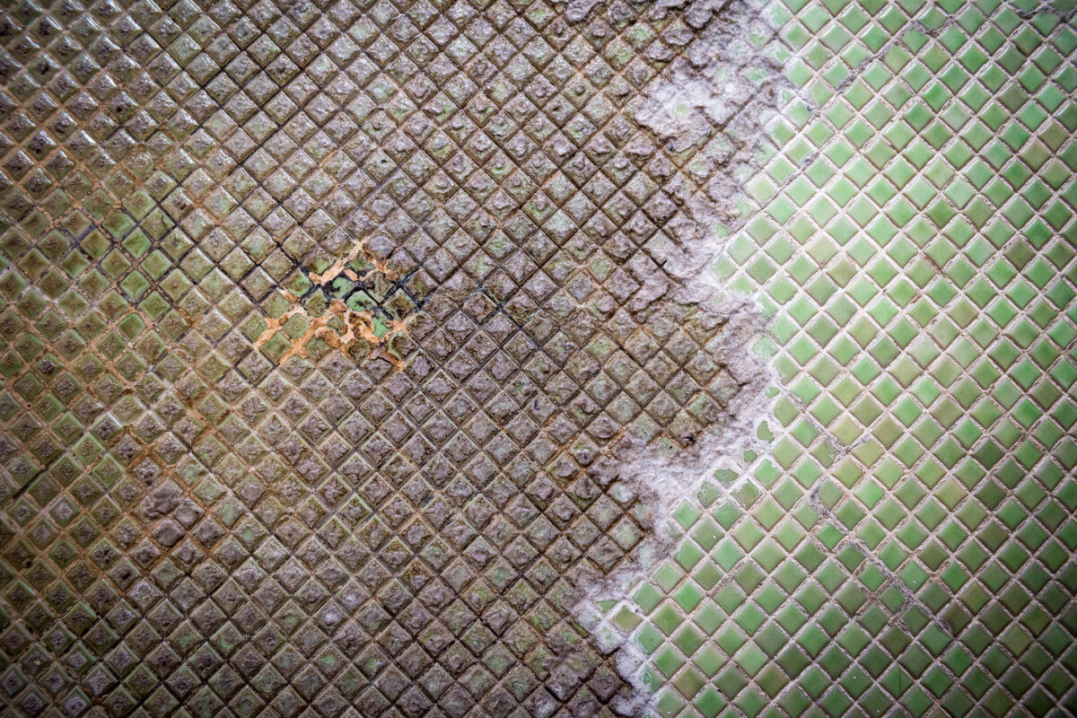 Close-up of weathered onsen bath tiles with mineral stains at Sekizenkan Ryokan, Japan
