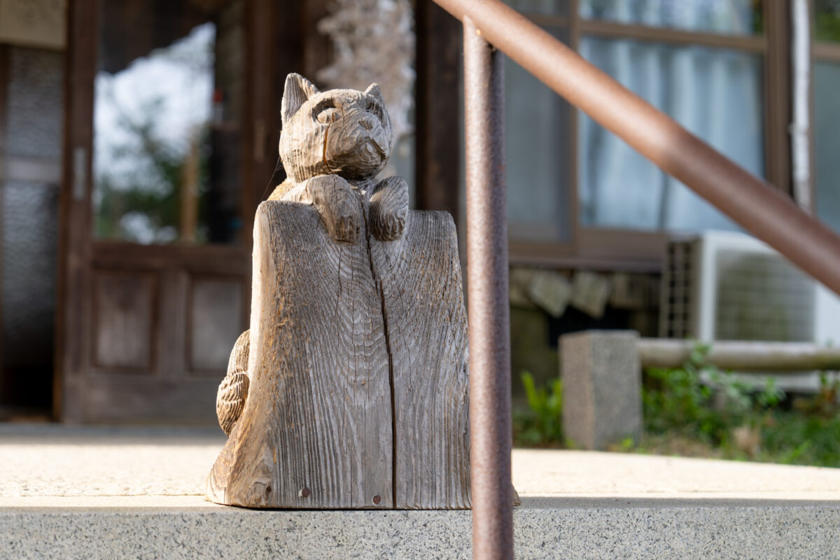 Weathered wooden cat guardian statue on Unrin-ji Buddhist temple veranda in Japan