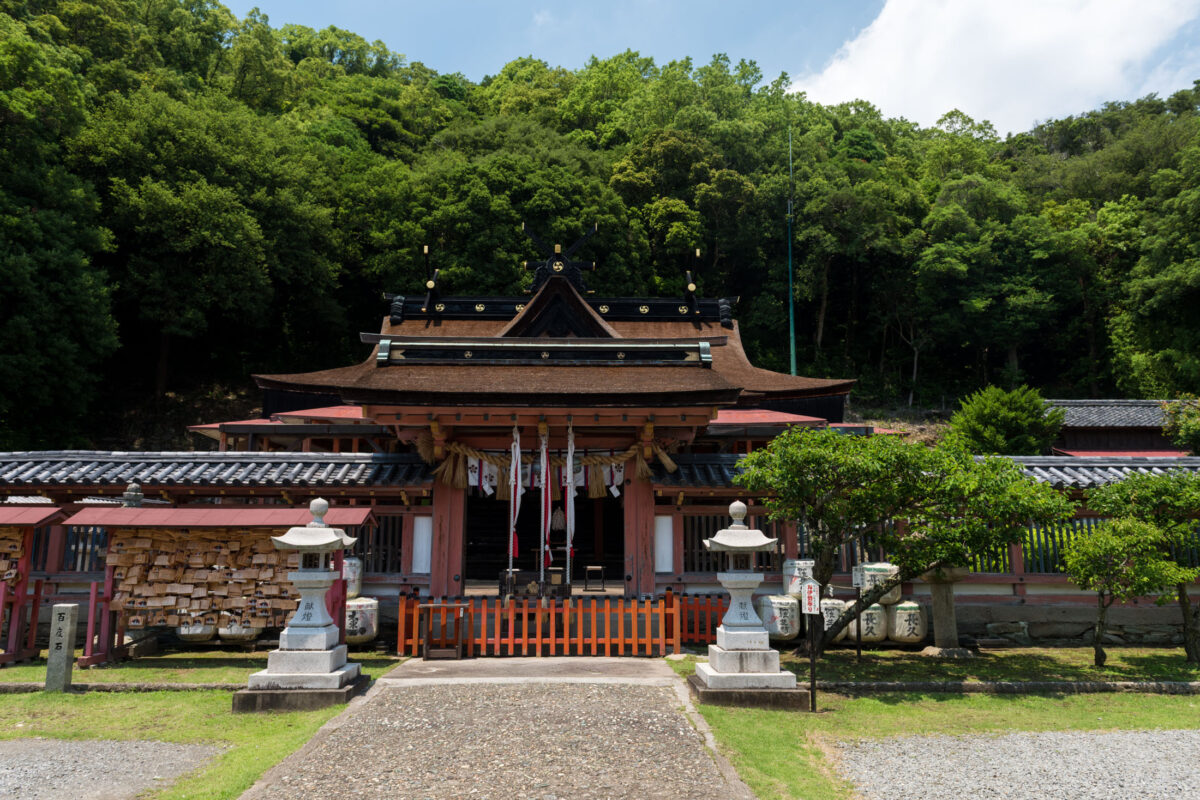 Stone path to Wakaura Tenmangu Shrine in Wakayama, Japan, with lanterns and forest backdrop.