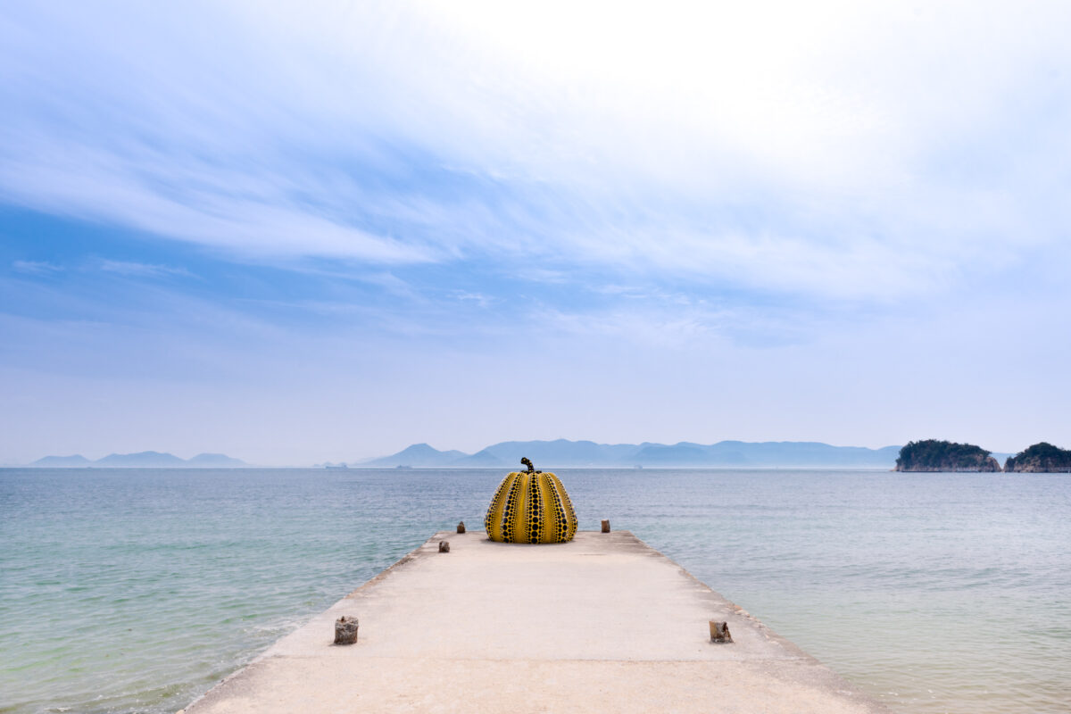 Yayoi Kusama yellow polka-dot pumpkin sculpture on pier at Naoshima, Japan
