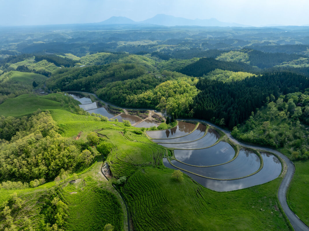 Aerial view of Ogi terraced rice paddies on green hills with reflective water fields